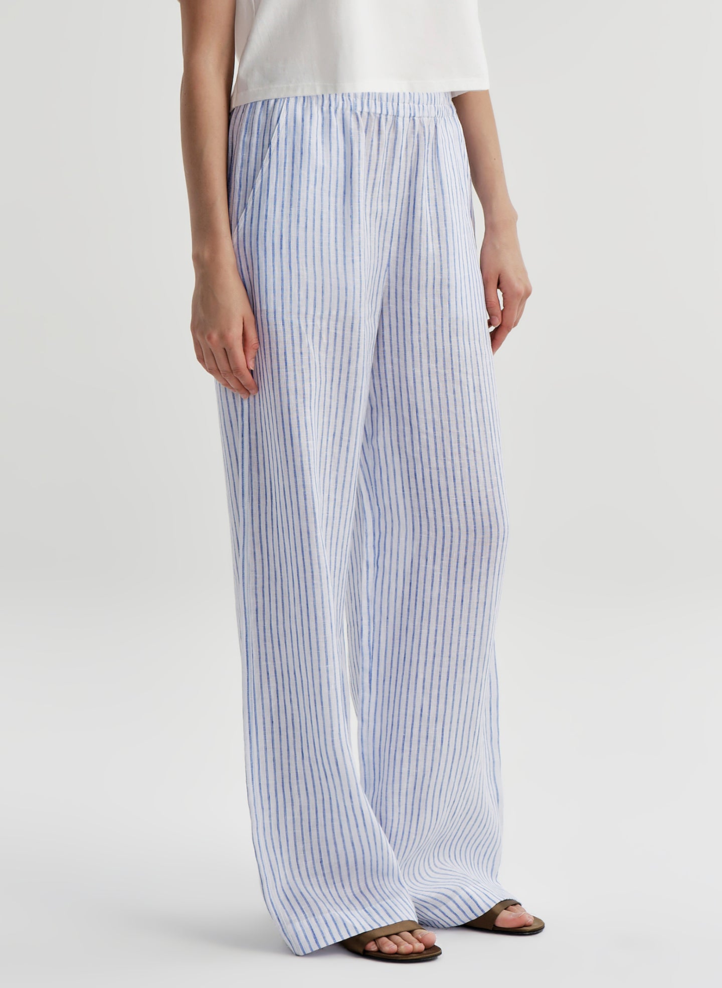 Woman wearing blue and white striped linen pants on a plain background