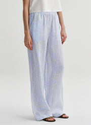 Woman wearing blue and white striped linen pants on a plain background