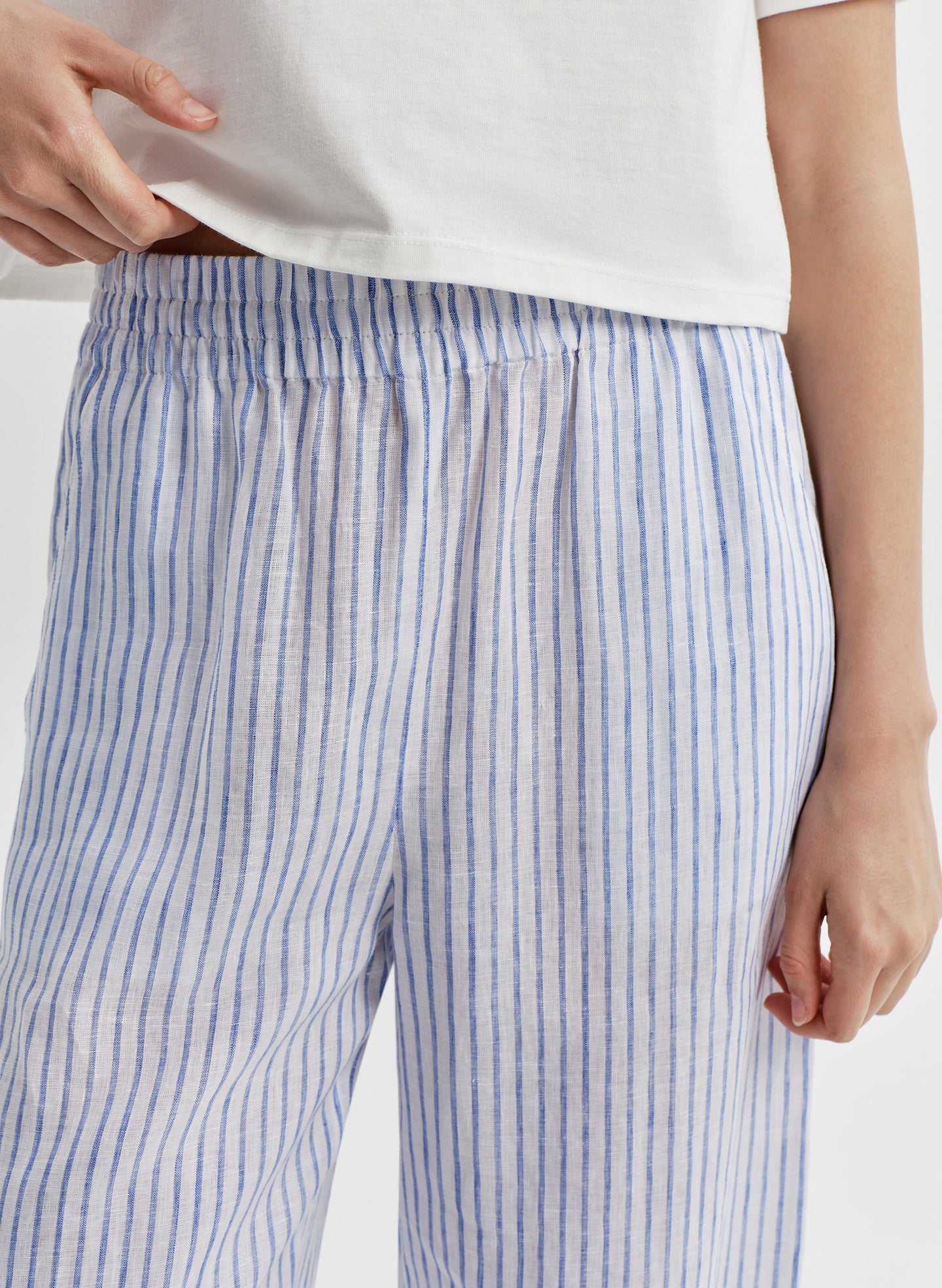 Blue and white striped linen pants on a light gray background