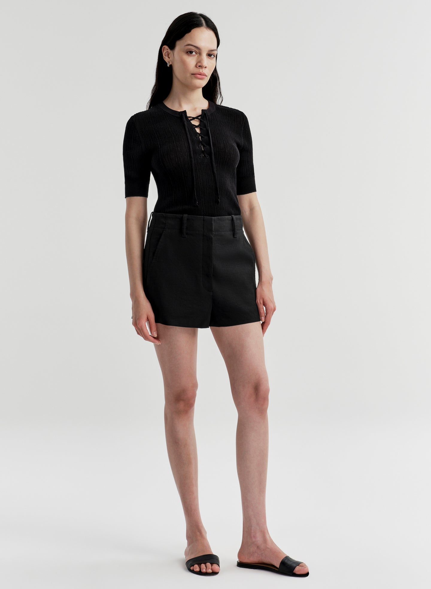 Woman wearing a black top with a black skirt on a plain background