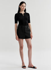 Woman wearing a black top with a black skirt on a plain background