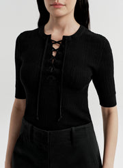 Person wearing a black lace-up top and on a white background