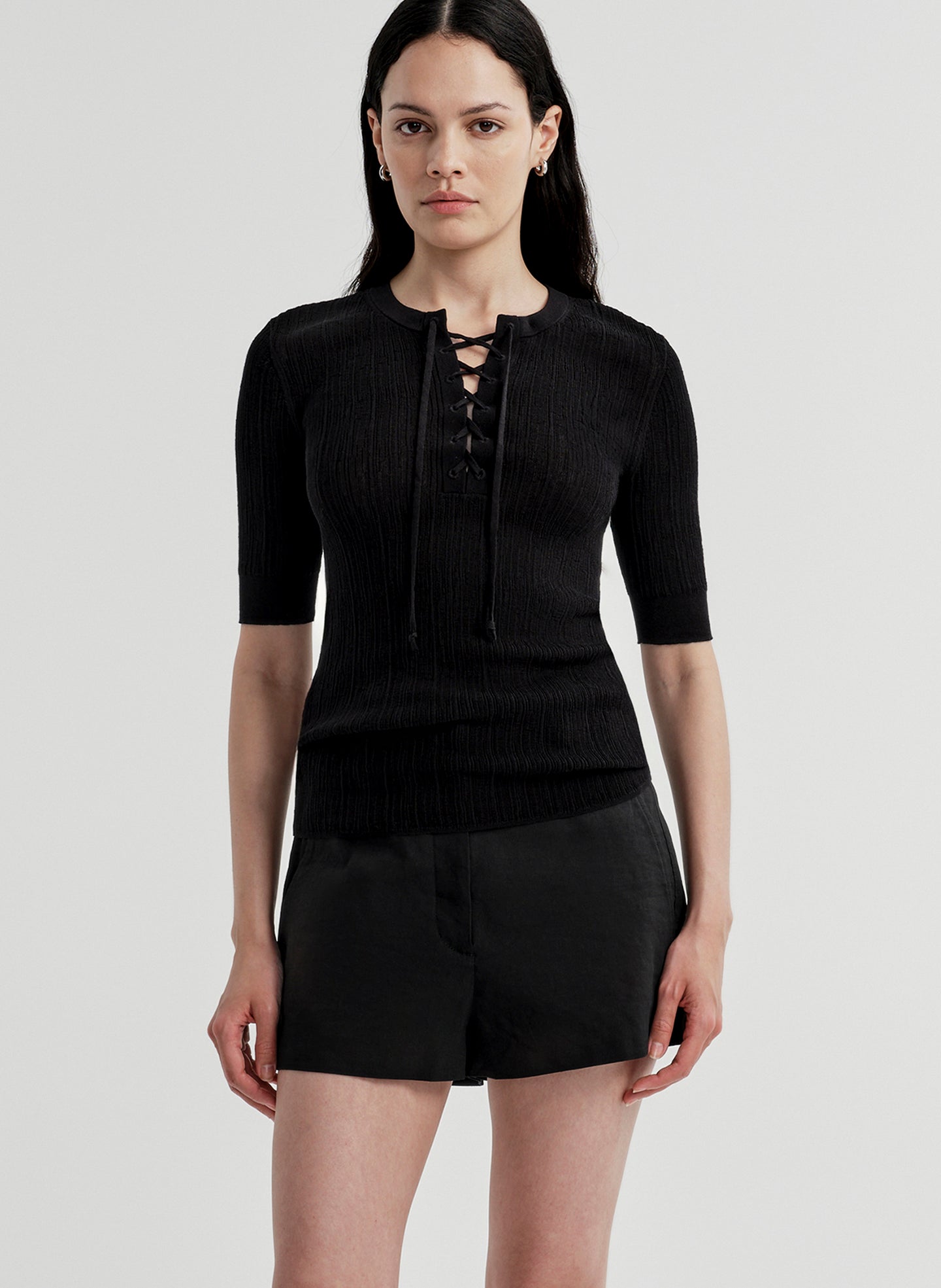 Woman wearing a black top with a black skirt on a plain background