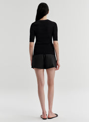 Woman wearing a black top with a black skirt on a plain background