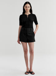Woman wearing black linen shorts and a black top on a white background