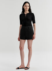 Woman wearing black linen shorts and a black top on a white background