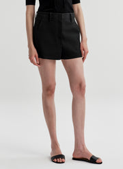 Woman wearing black linen shorts and a black top on a white background