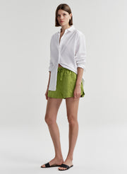 Woman wearing green shorts and a white shirt