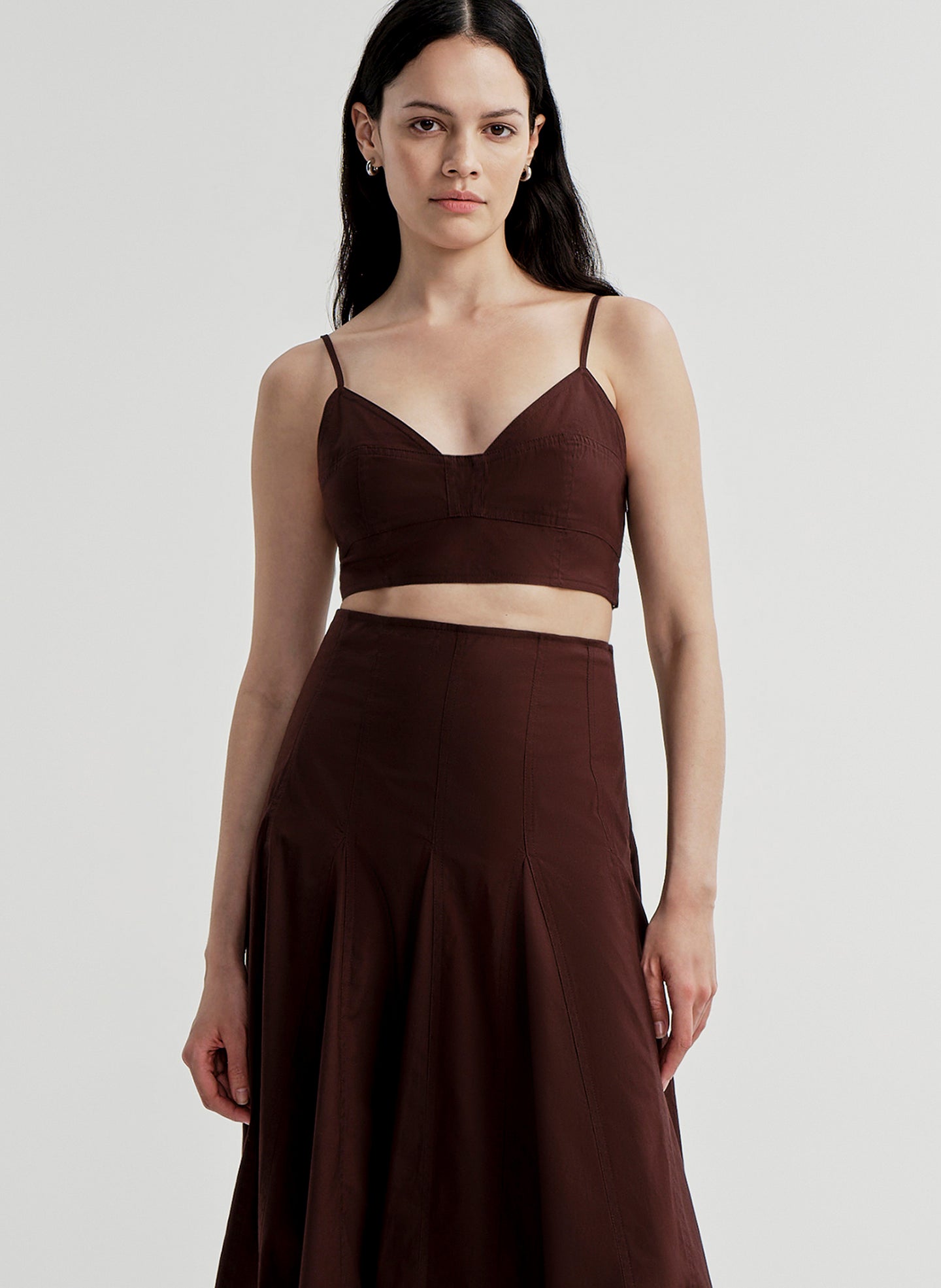 Woman wearing a brown top and skirt set on a light gray background