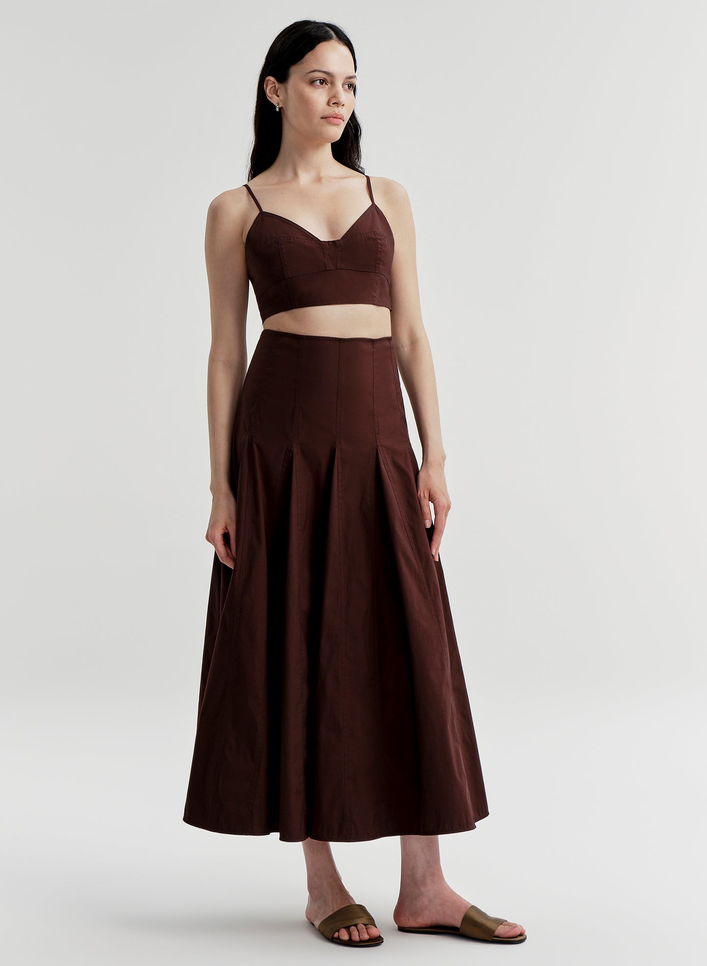 Woman wearing a brown top and skirt set on a light gray background