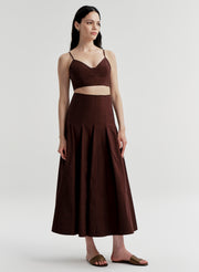 Woman wearing a brown top and skirt set on a light gray background