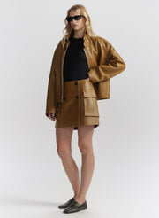 Woman wearing a gold coat and sunglasses on a white background