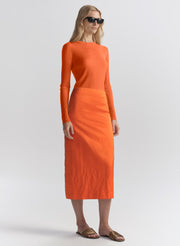 woman wearing orange top and matching midi skirt