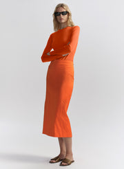 woman wearing orange top and matching midi skirt