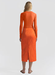 woman wearing orange top and orange midi skirt