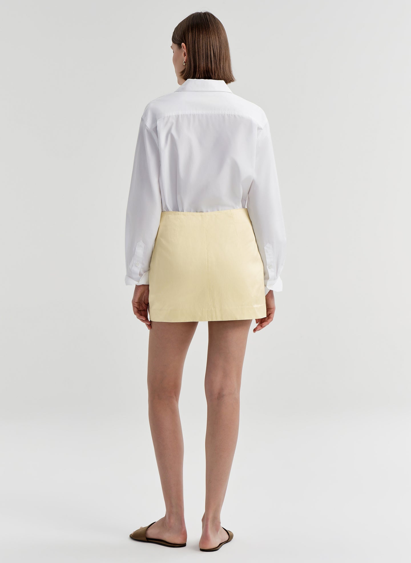 woman wearing white shirt and yellow satin mini skirt