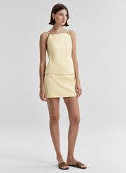 Woman wearing a light yellow top and mini skirt on a white background