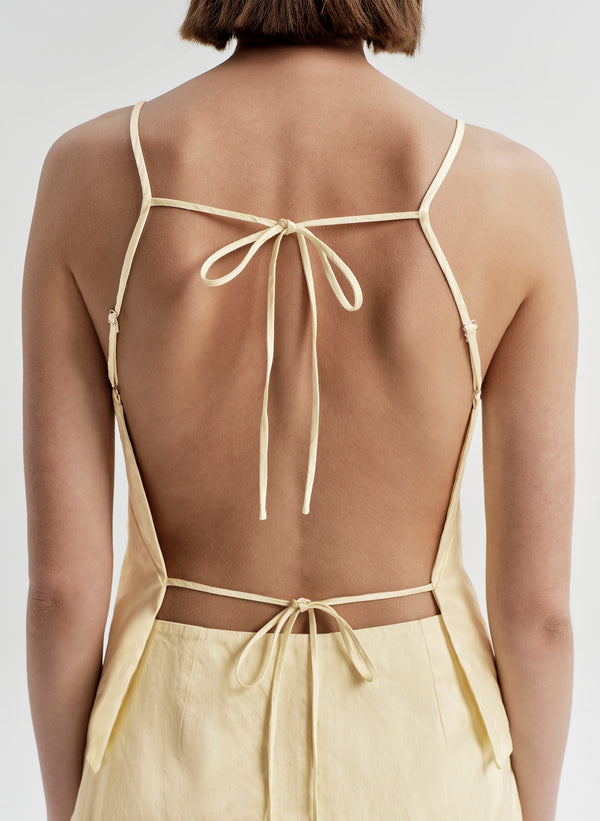 Woman wearing a light yellow top and mini skirt on a white background