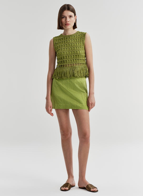 Woman wearing a green sleeveless top and skirt on a white background