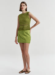 Woman wearing a green sleeveless top and skirt on a white background