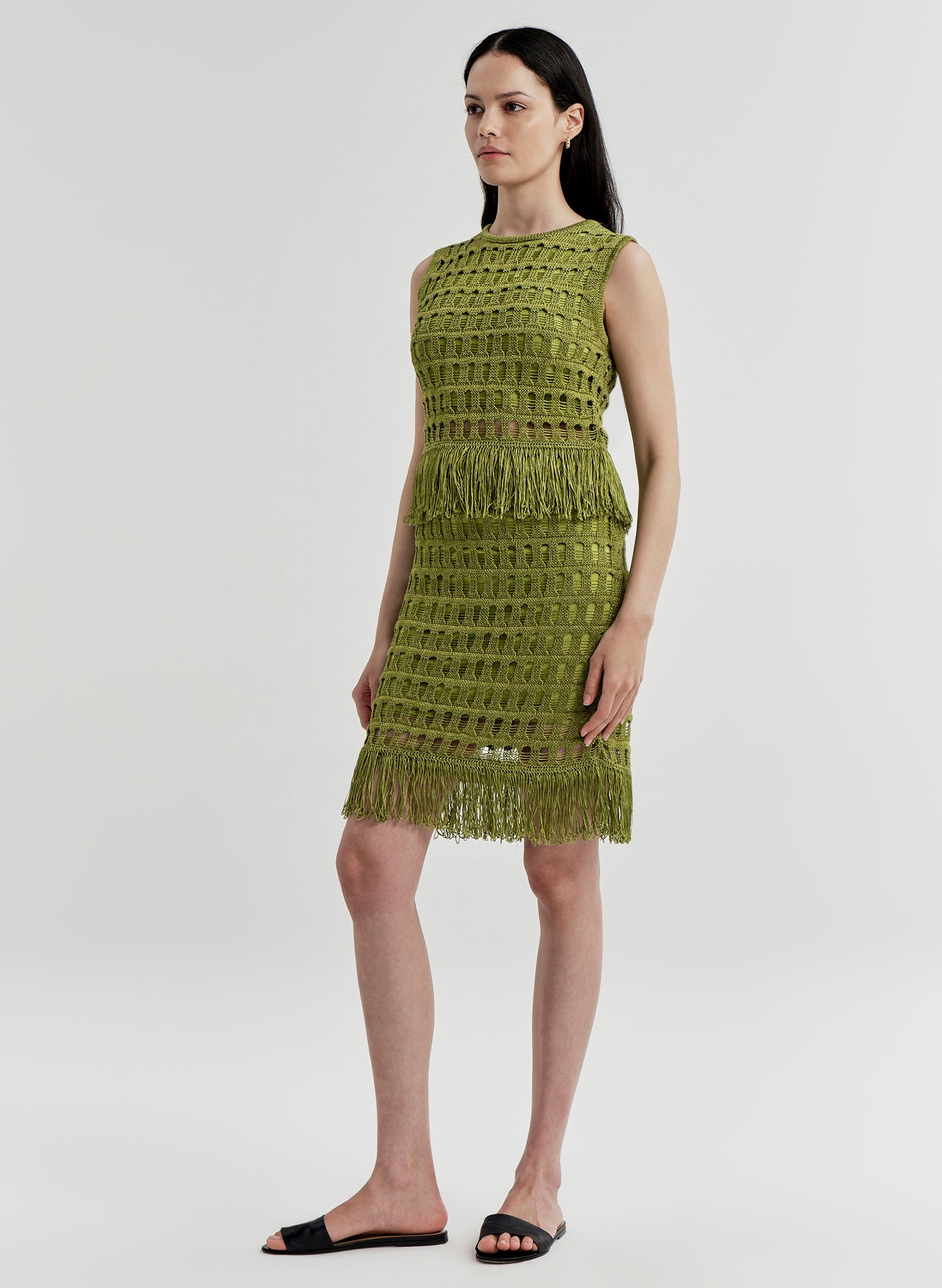 Woman wearing a green crochet mini skirt with matching top on a white background