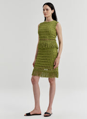 Woman wearing a green crochet mini skirt with matching top on a white background