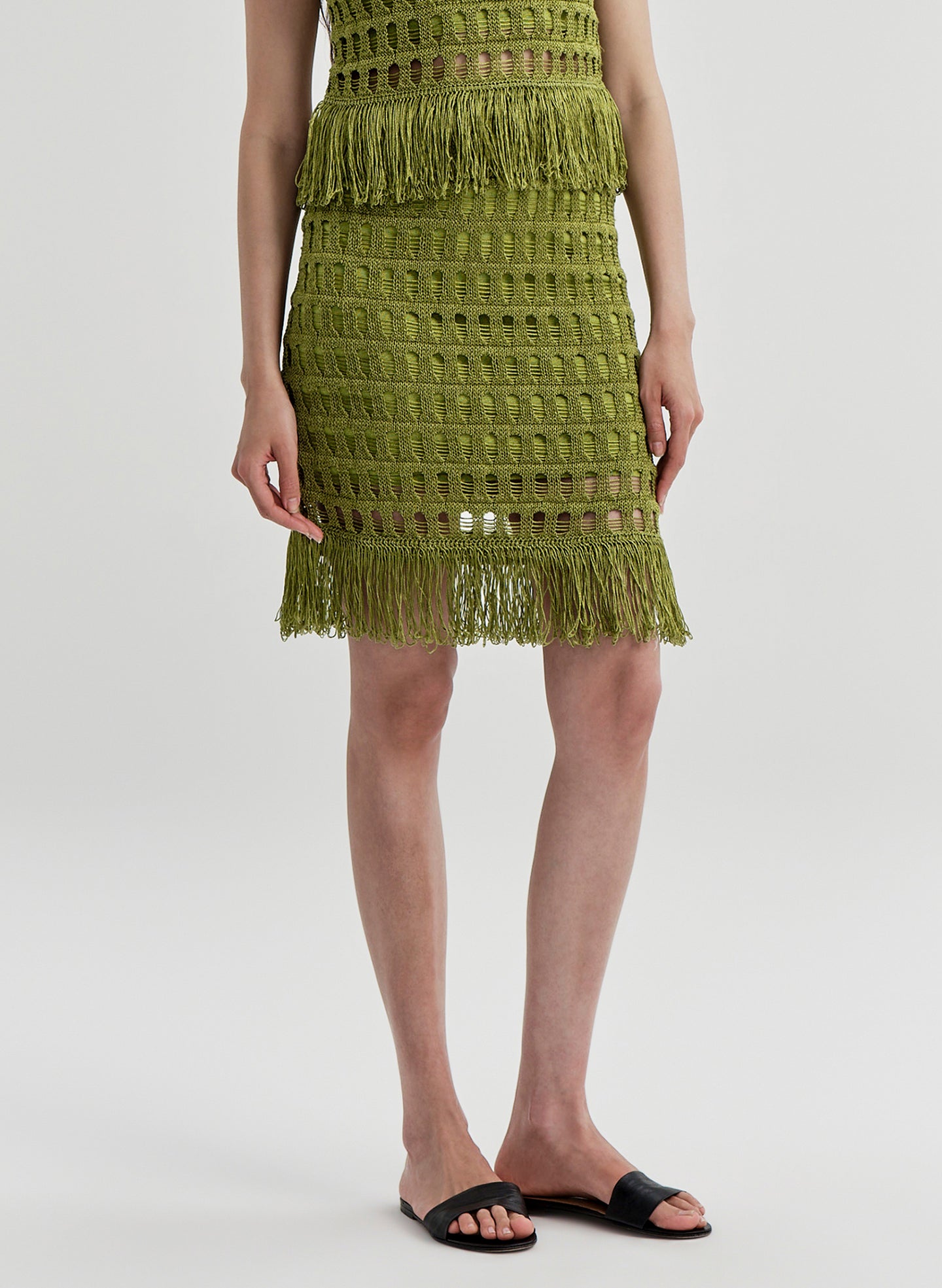 Woman wearing a green crochet mini skirt on a white background