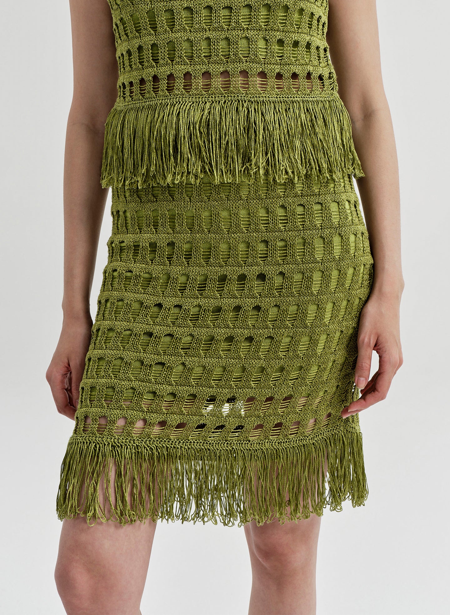 Woman wearing a green crochet mini skirt on a white background