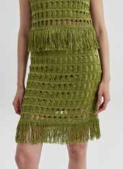 Woman wearing a green crochet mini skirt on a white background