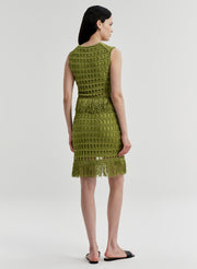 Woman wearing a green crochet mini skirt with matching top on a white background