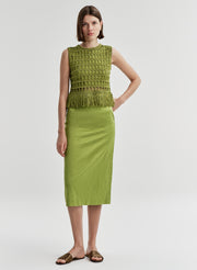 Woman wearing a green skirt with a green sleeveless top on a white background