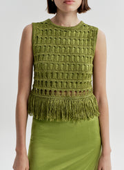 Woman wearing a crochet green sleeveless top with fringe details on a light gray background