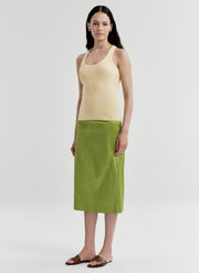 Woman wearing a yellow tank top and green skirt on a white background