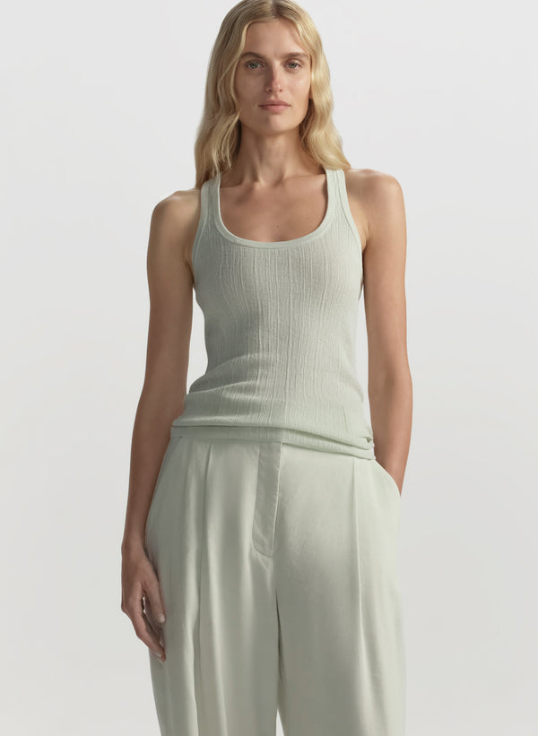 Woman wearing a light green ribbed tank top and wide-leg pants against a plain background