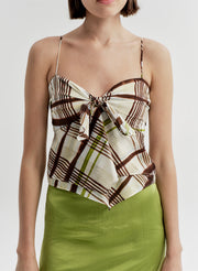 Woman wearing a patterned brown top and green skirt on a plain background