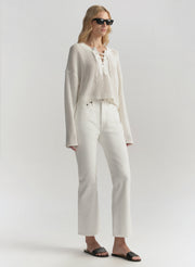 Woman wearing a white outfit with sunglasses on a plain background