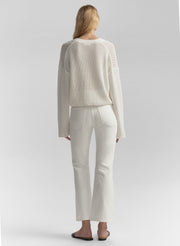 Woman wearing a white textured top and pants on a light gray background