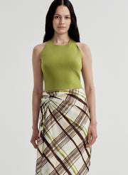 Woman wearing a green halter top and plaid skirt on a light gray background