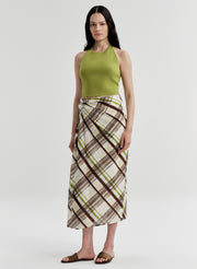 Woman wearing a green halter top and plaid skirt on a light gray background