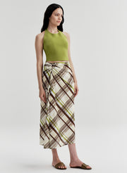 Woman wearing a green halter top and plaid skirt on a light gray background