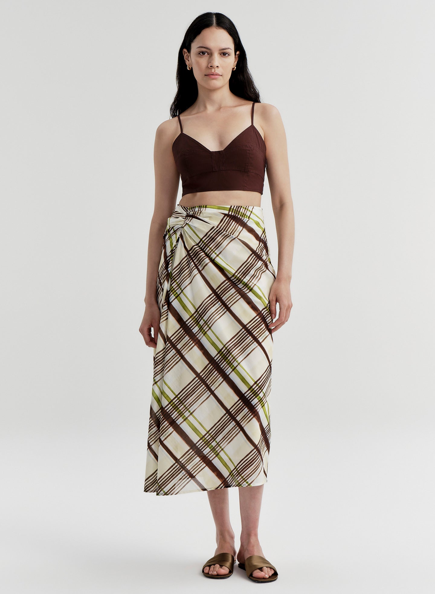 Woman wearing a brown and green plaid skirt on a white background