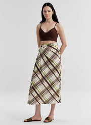 Woman wearing a brown and green plaid skirt with a plain background