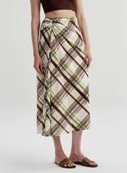 Woman wearing a plaid brown and green skirt on a plain background