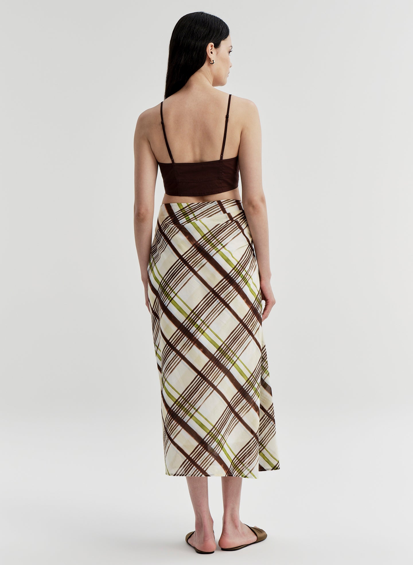 Woman wearing a plaid skirt and brown top on a white background