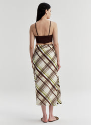 Woman wearing a plaid skirt and brown top on a white background