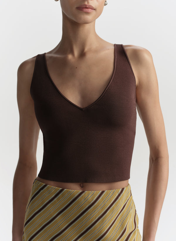 Woman wearing a brown tank top and striped skirt on a white background