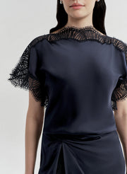 Navy blue top with lace sleeves on a plain background