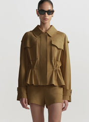 Person wearing a brown jacket and shorts set with sunglasses on a white background