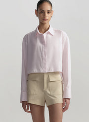 Person wearing a light pink shirt and beige shorts on a plain background