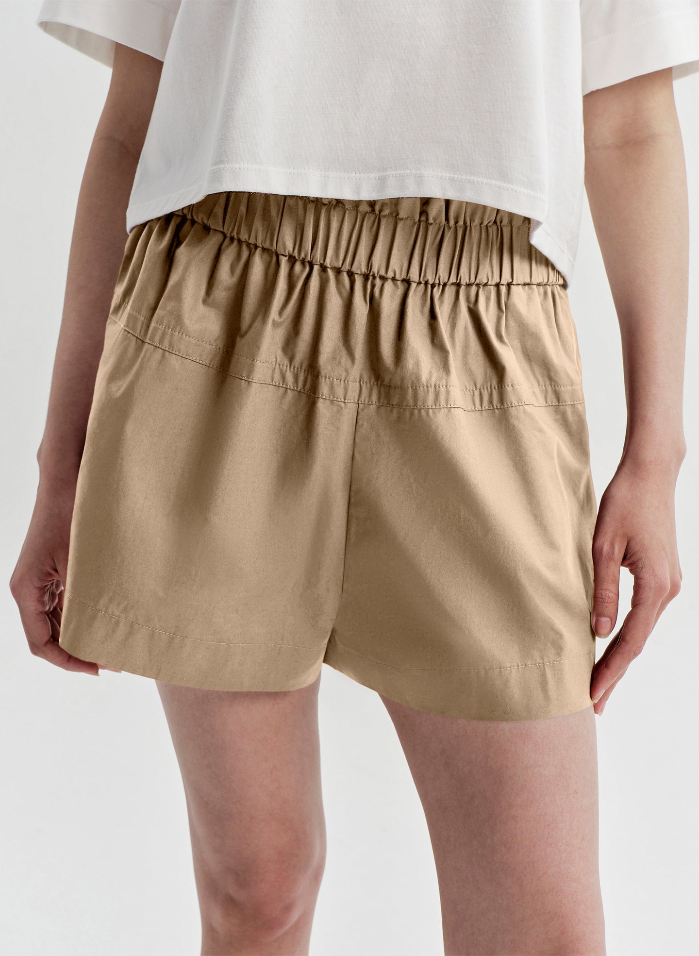 Beige shorts worn by a person on a white background